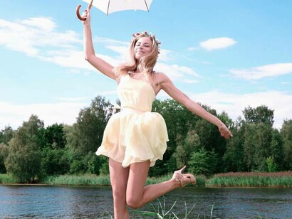 A woman smiling and feeling happy as she holds an umbrella on a sunny day