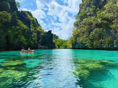 Kayakers drifting across the turquoise lagoon of El Nido, Palawan, symbolising the harmony between people and the environment
