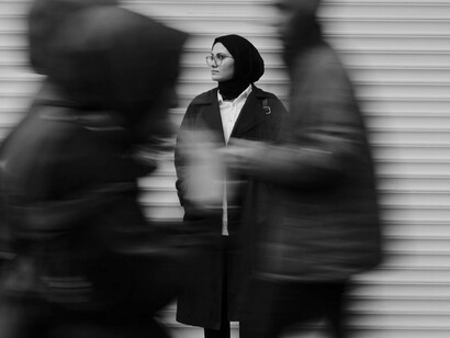 A woman standing calmly as crowds pass by, representing the power of finding inner stillness in a fast-moving world