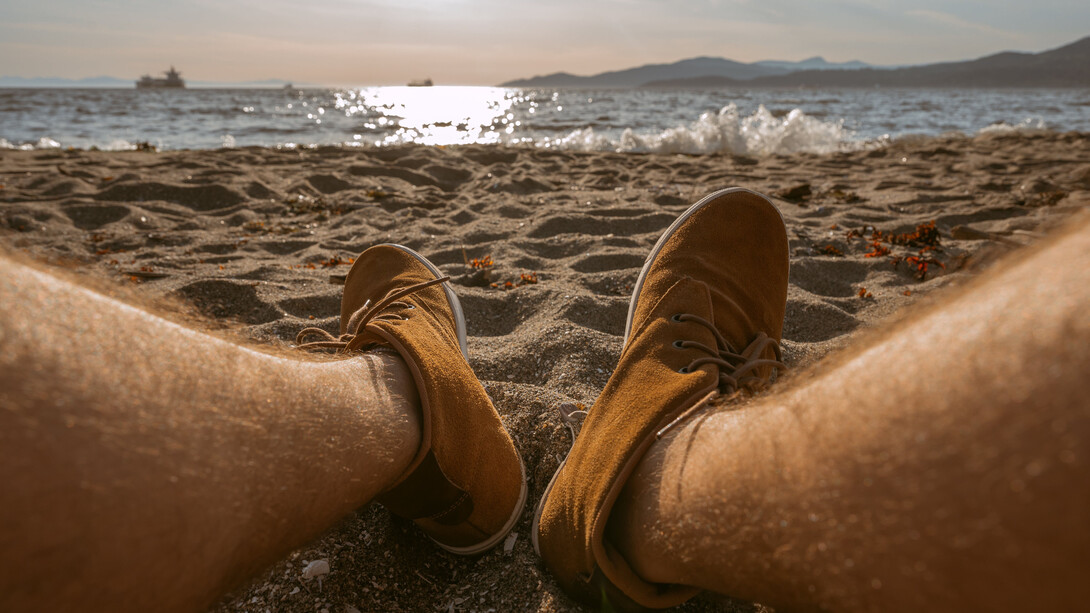 Pai de família com os pés na areia em um dia de praia com os filhos