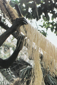 Homme tissant du raphia sur un métier à tisser au Congo