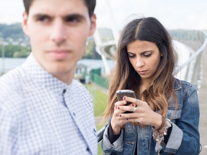 Un joven aburrido mientras su pareja solo mira el móvil