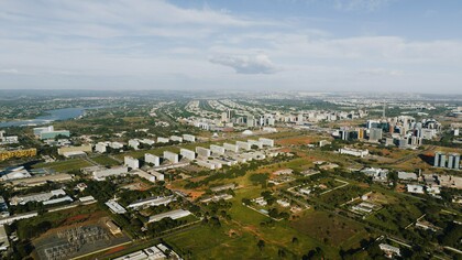 Do alto, Brasília revela o contraste entre o desenho urbano planejado e a expansão que se estende para além de seus limites. Ao fundo, as cidades-satélite aparecem distantes do núcleo original, evidenciando como o crescimento efetivo pode assumir trajetórias diferentes daquelas previstas pelo planejamento