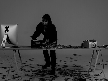 A woman surrounded by piles of cash on a table, symbolizing an abstract concept of money laundering