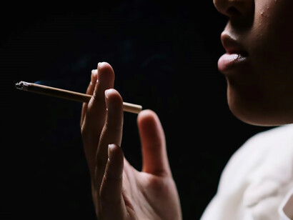 A captivating close-up: a woman sporting white sleeves and eyeglasses, immersed in a moment of smoking allure