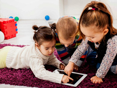 Un grupo de niños juegan con la pantalla táctil de una tableta