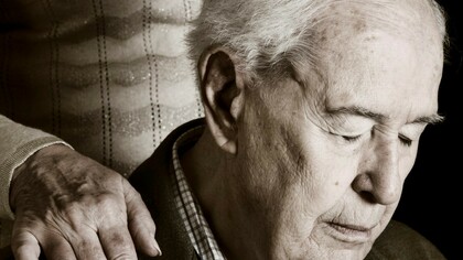 Una mujer anciana apoya su mano sobre el hombro de su marido