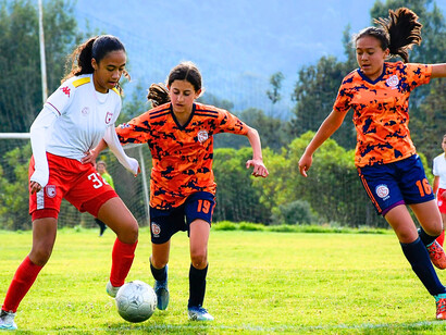 A lively girls’ football team chasing the ball, reflecting the carefree nature of childhood competition