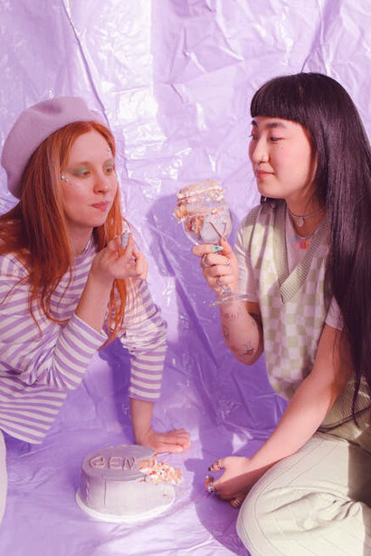 Two friends dig into cake decorated with 'Gen Z' as they explore the exciting intersection of technology and fashion in today’s rapidly evolving landscape