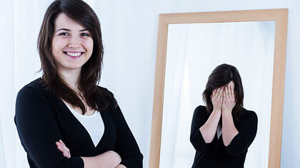 Woman smiling while reflection has hands over face