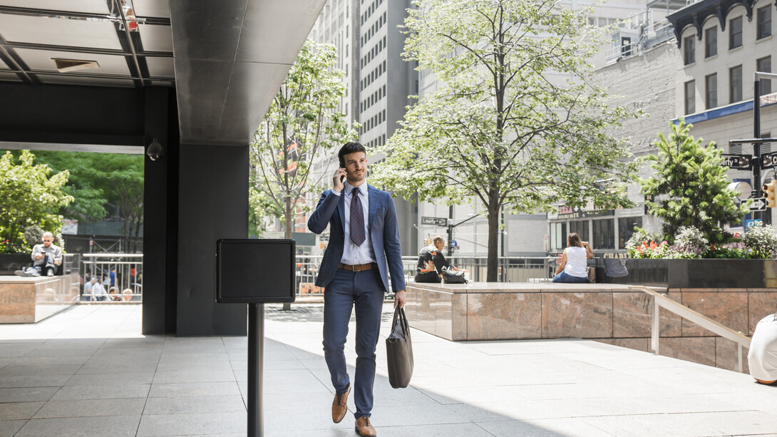 Businessman walking away from the office while speaking on the phone