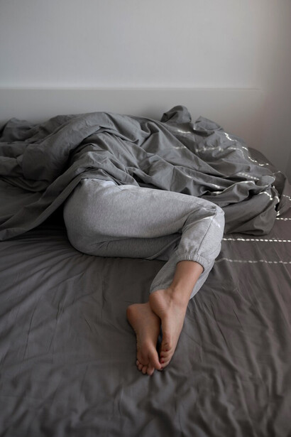 An image of a depressed woman curled up in a blanket on her bed, symbolizing the need for compassion and support in mental health awarenes