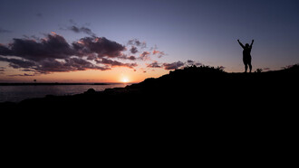 Un uomo alza le braccia verso l'orizzonte 