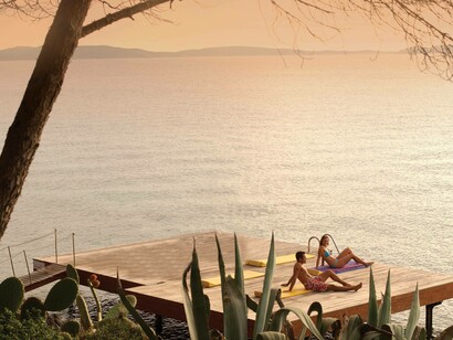 A couple are relaxing by the sea in one of Capo d'Orso's more secluded and relaxing deck areas in Sardinia