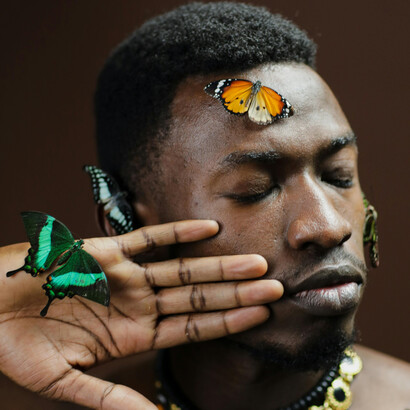 A serene, poetic portrait of a topless man immersed in nature, where butterflies drift around him as symbols of transformation and harmony