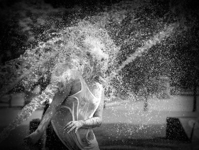 A woman in Portland, Oregon, USA walks straight through a spout of water to cool down during the summer heat