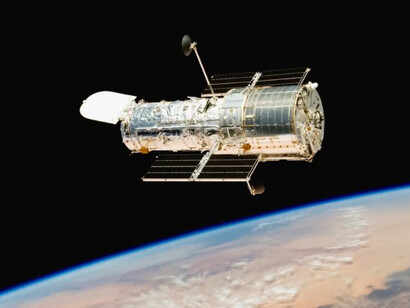 Hubble From Behind (2009) Caption The Space Shuttle Atlantis moves away from Hubble after the telescope's release on May 19, 2009 concluded Servicing Mission 4. The Soft Capture Mechanism, a ring that a future robotic mission can grapple in order to de-orbit the telescope, is visible in the center
