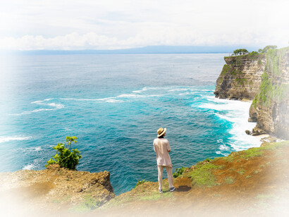 A man stands on the cliffs overlooking the ocean, thinking of nature