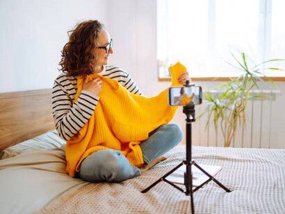 Fashion blogger recording new content for vlog with camera holding yellow sweater