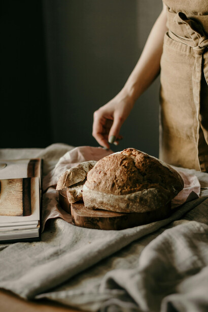 A woman stands in her kitchen, preparing to slice a loaf of homemade sourdough bread