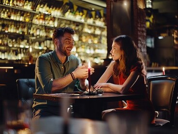 A happy young couple shares a lively conversation during an evening date at a modern pub