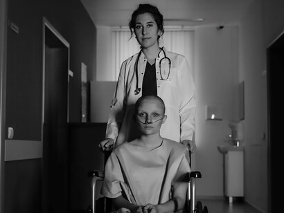 A patient, confined to a wheelchair, navigates the hospital corridor with a determined yet hopeful gaze
