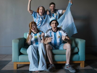 Fans wrapped in the Argentine flag as they cheer together, symbolizing the emotional bond between national identity and the game