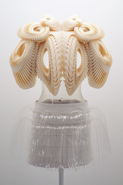 Iris van Herpen’s autumn/winter 2011-12 haute couture ensemble (edition 2015) features a 3D-printed white polyamide top shaped like spiraling shells, paired with a white cow leather skirt trimmed with clear acrylic fringe
