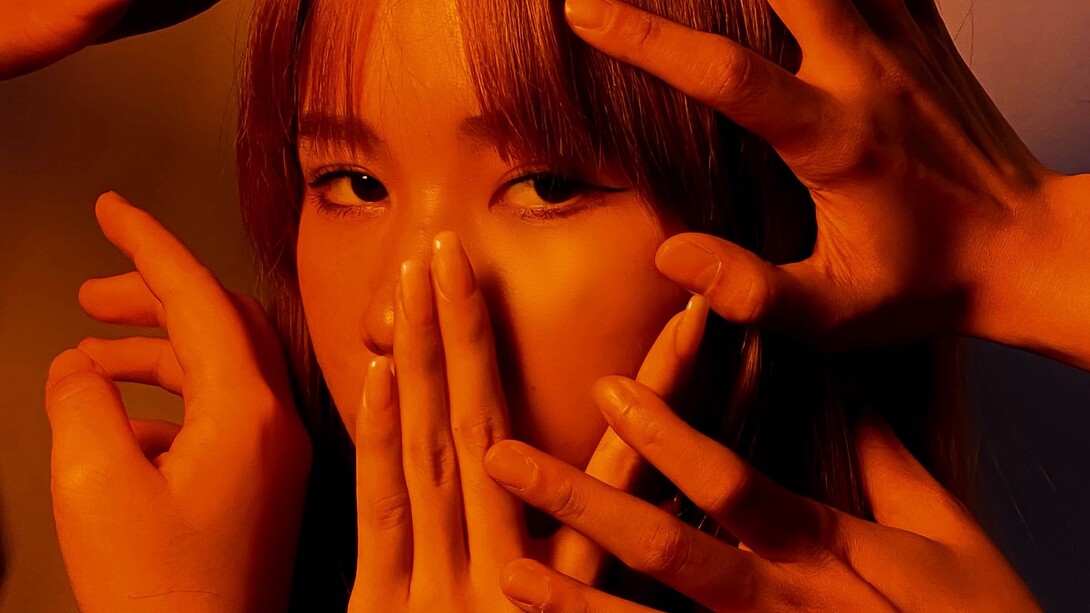 Young girl sadly gazes into the distance as her face is covered by hands