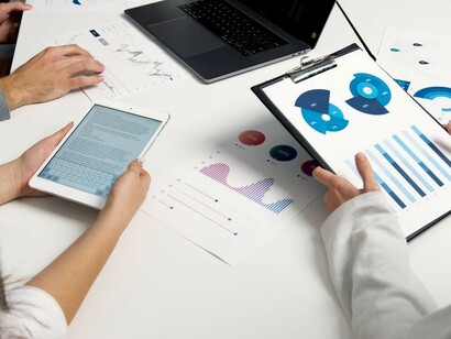 Economists conducting analysis while reviewing a screen filled with graphs