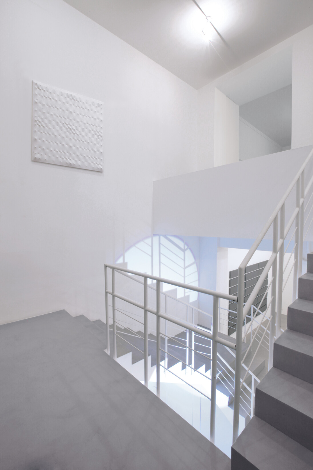 (dall’alto verso il basso) Enrico Castellani,
Superficie bianca, 1990 Acrilico su tela estroflessa, 120x120 cm. Michel Verjux, Contre-plongée traversante, à l’escalier (source au sol), 2015 Proiettore. Alan Charlton, 24 Horizontal parts, 2010 Acrilico su tela, 211,5x319,5 cm. Veduta parziale dell’esposizione A arte Invernizzi. Courtesy A arte Invernizzi, Milano. Foto Bruno Bani