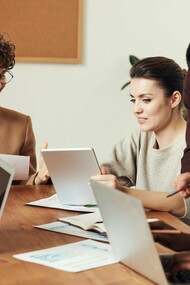 Employees gathered around a table, working together with visible energy, highlighting the motivation that comes from having a stake in the outcome