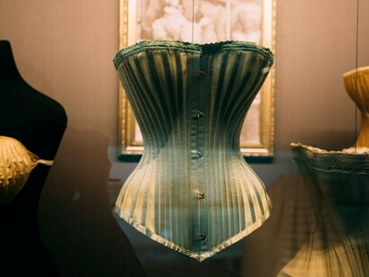 A collection of antique corsets displayed on mannequins in a showcase