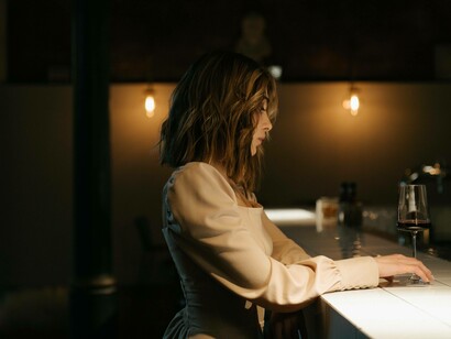 A woman embracing the single life by going to a bar and enjoying a glass of red wine