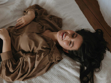 A gentle portrait of self-discovery—a person smiling in bed, representing personal truth, self-acceptance, and emotional honesty