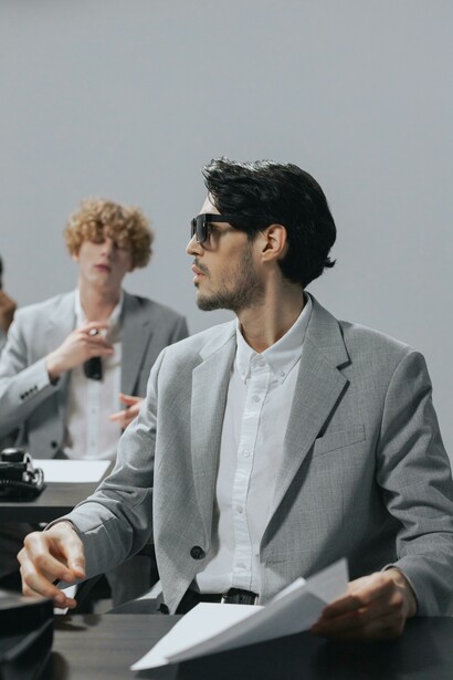 A group of men in an office, present but distant, each absorbed in their own world