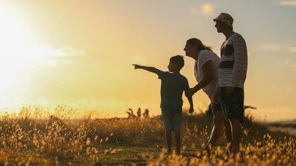 Una familia mira hacia el sol que se esconde durante el atardecer. La primera unidad de interacción es la familia donde se desarrolla el ser espiritual