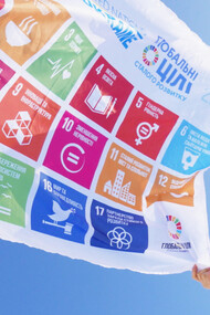 A woman holds a flag of the SDG of the UN