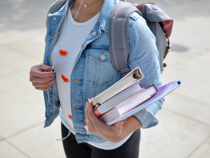 Mujer se dirige a estudiar con sus libros en mano mientras escucha música