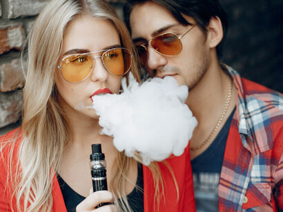 A young couple vaping in the city, with vapor swirling around them