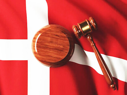 The gavel resting beside the Danish flag encapsulates the essence of the country's constitution and the concept of justice