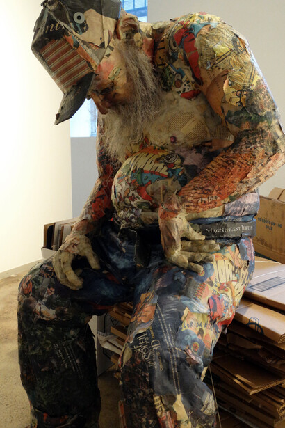 Sleeping Homeless Guy, 2015. Wood, wire, newspaper, glue, tape, matte medium, UV matte varnish, 33 x 24 x 48 inches and boxes
