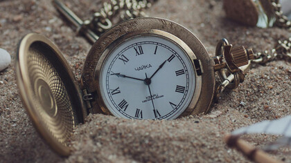A pocket watch sunk in the sand