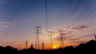 Electricity pylons standing tall against the evening sky, representing the strategic importance of grid resilience and capacity