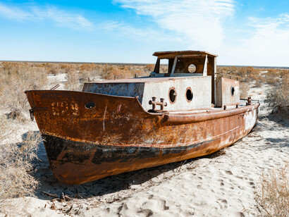In Muynaq, Uzbekistan, a stranded rusty ship sits on the dry seabed of the Aral Sea, serving as a powerful symbol of drought and ecological destruction