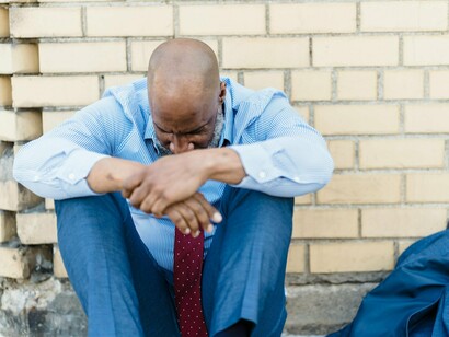 An exhausted worker sitting with his head buried in his arms, representing the growing despair caused by economic hardship and political stagnation