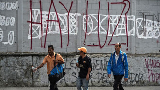 Ciudadanos sonríen al mirar un grafiti que hace alusión a los frecuentes apagones registrados en Venezuela