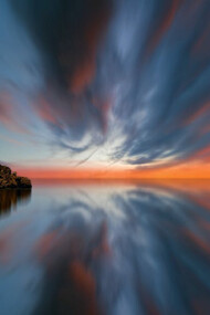 Bathed in the ethereal glow of a sunset, the island stands as a doorway to a timeless realm where light and shadow merge
