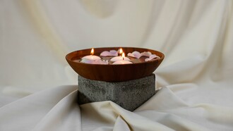 Tigela de madeira com velas acesas e pétalas