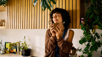 Woman savoring her morning coffee in a bright, modern kitchen, embracing mindfulness and finding joy in the simple pleasures of everyday life